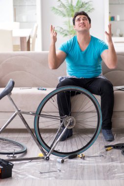 Evde bisiklet tamir eden genç bir adam.