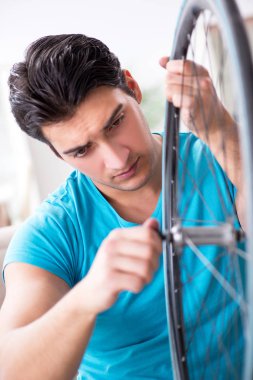 Evde bisiklet tamir eden genç bir adam.