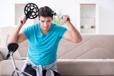 Evde bisiklet tamir eden genç bir adam.