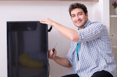 Evdeki bozuk televizyonu tamir eden adam.