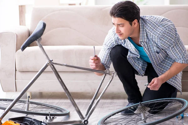 Evde bisiklet tamir eden genç bir adam.