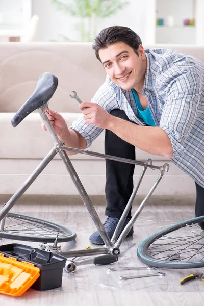 Evde bisiklet tamir eden genç bir adam.