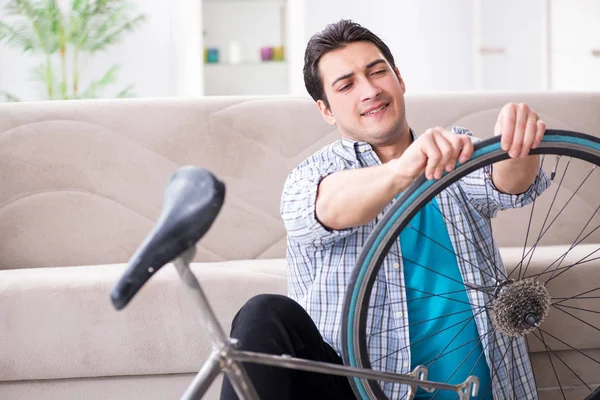 Evde bisiklet tamir eden genç bir adam.