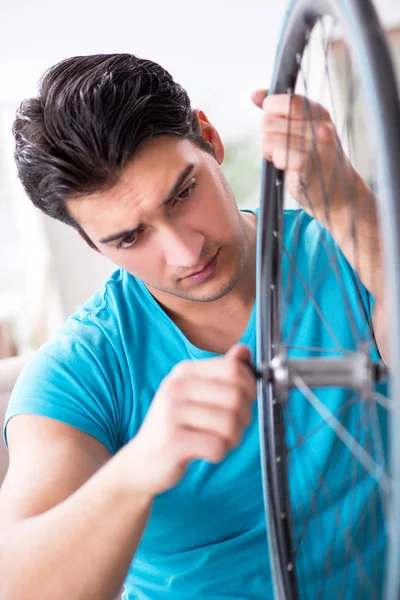Evde bisiklet tamir eden genç bir adam.