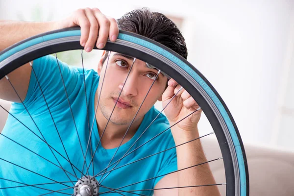 Evde bisiklet tamir eden genç bir adam.