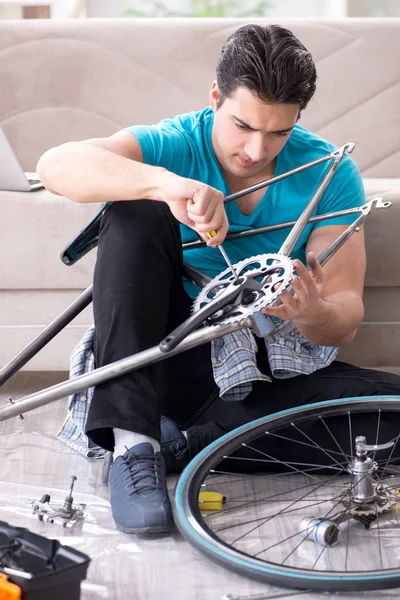 Jovem reparando bicicleta em casa — Fotografia de Stock