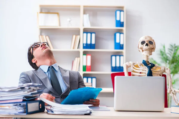 Бізнесмен, що працює зі скелетом в офісі — стокове фото
