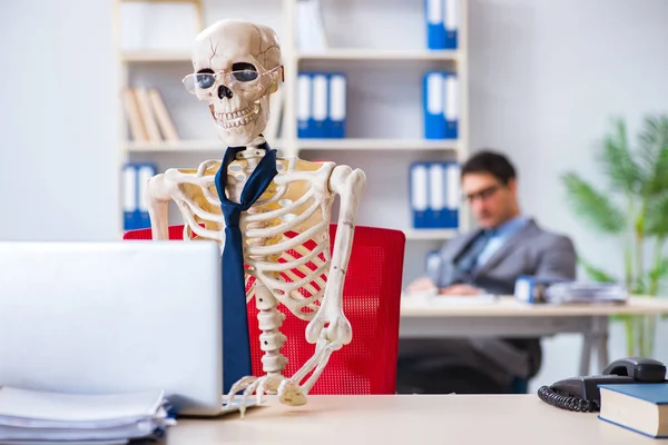 Biznesmen pracujący ze szkieletem w biurze — Zdjęcie stockowe