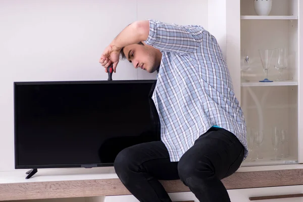 Evdeki bozuk televizyonu tamir eden adam.