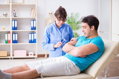 Doktor çekiçle sinir reflekslerini kontrol ediyor