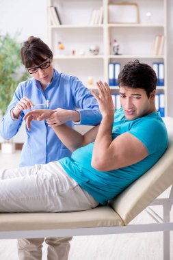 Doktor çekiçle sinir reflekslerini kontrol ediyor