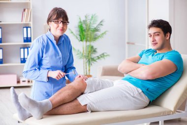 Doktor çekiçle sinir reflekslerini kontrol ediyor