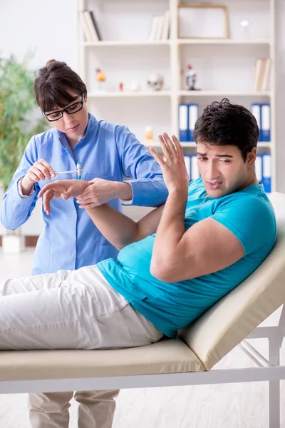 Doktor çekiçle sinir reflekslerini kontrol ediyor