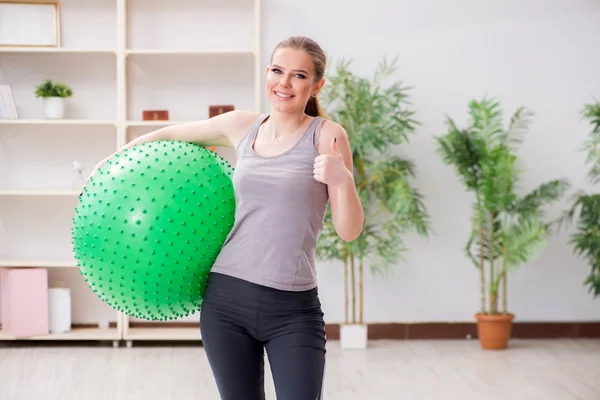 Young woman exercising with stability ball in gym