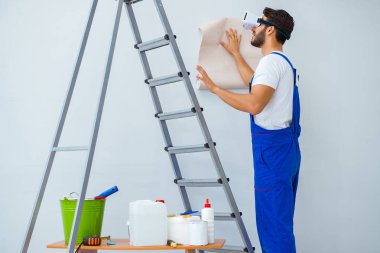 VR gözlüklü, duvar kağıdı yapıştıran bir adam.