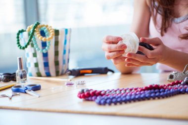 Kadın evde mücevher yapıyor.