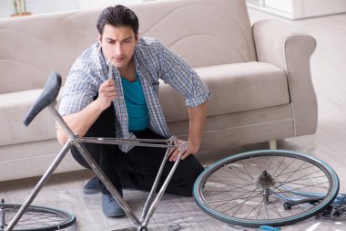 Evde bisiklet tamir eden genç bir adam.