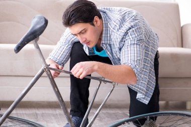 Evde bisiklet tamir eden genç bir adam.