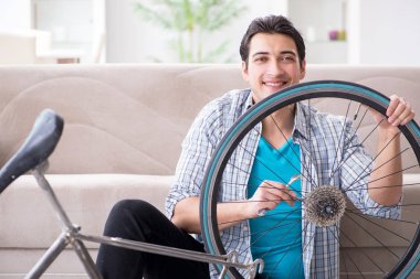 Evde bisiklet tamir eden genç bir adam.