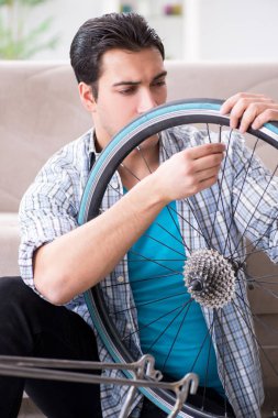 Evde bisiklet tamir eden genç bir adam.