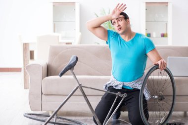 Evde bisiklet tamir eden genç bir adam.