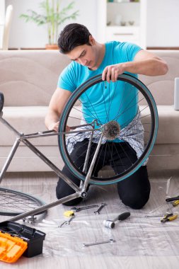 Evde bisiklet tamir eden genç bir adam.