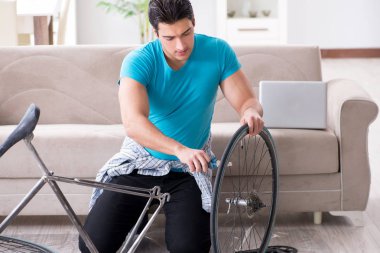 Evde bisiklet tamir eden genç bir adam.