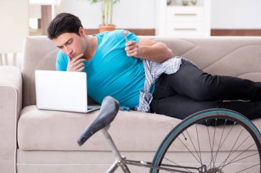 Evde bisiklet tamir eden genç bir adam.