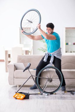 Evde bisiklet tamir eden genç bir adam.