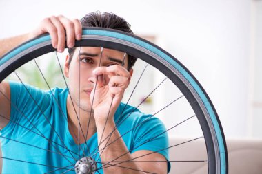 Evde bisiklet tamir eden genç bir adam.