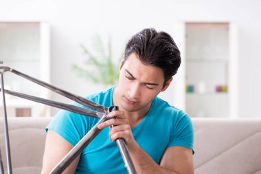 Evde bisiklet tamir eden genç bir adam.