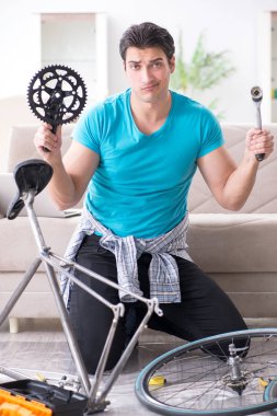 Evde bisiklet tamir eden genç bir adam.