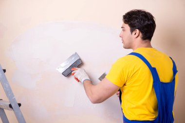 Duvara alçı yapıştıran genç müteahhit.