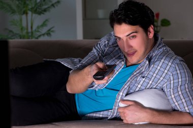 Genç adam gece geç saatte televizyon izliyor.