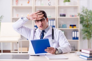 Genç doktor ofiste oturuyor.