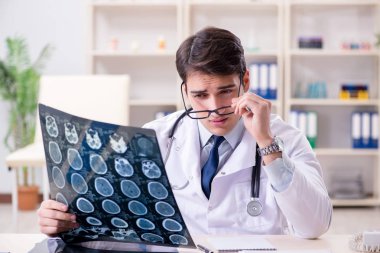 Genç doktor klinikteki röntgen görüntülerine bakıyor.