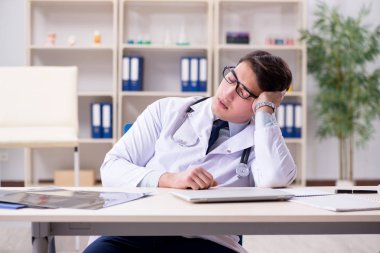 Genç doktor ofiste oturuyor.