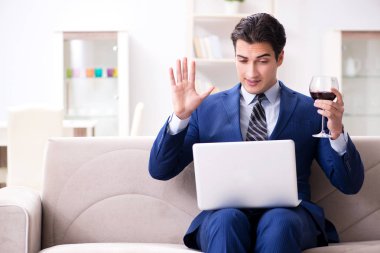 İş adamı evde oturmuş şarap içiyor.