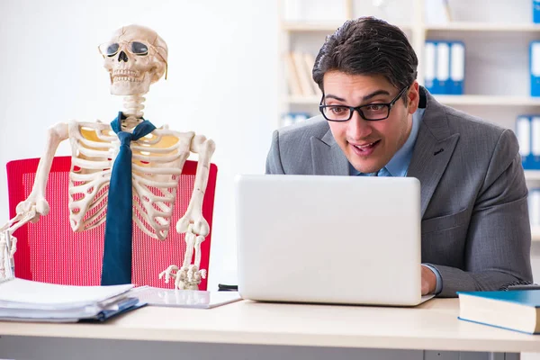 Бізнесмен, що працює зі скелетом в офісі — стокове фото