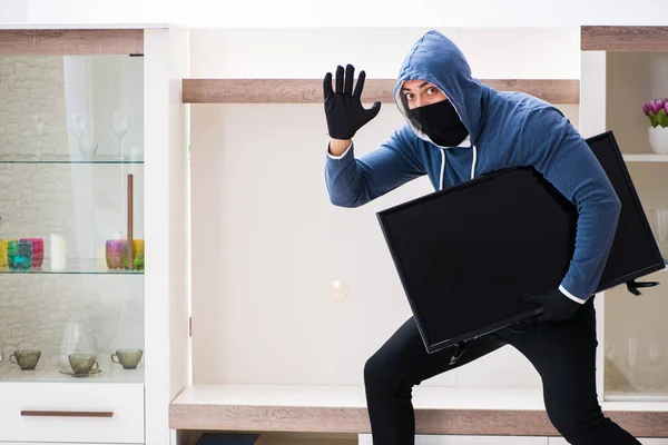 Человек-грабитель крадет телевизор из дома — стоковое фото