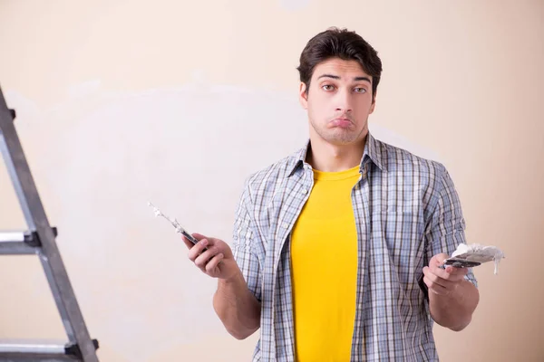 Hombre joven aplicando yeso en la pared en casa —  Fotos de Stock