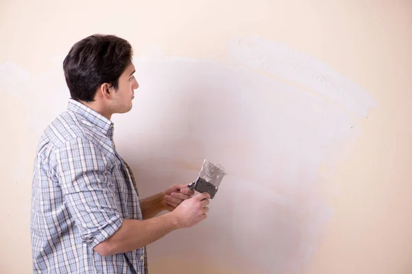 Hombre joven aplicando yeso en la pared en casa — Foto de Stock