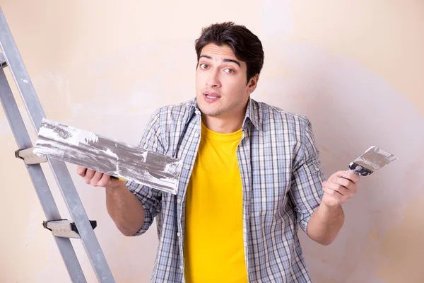 Молодий чоловік наносить штукатурку на стіну вдома — стокове фото