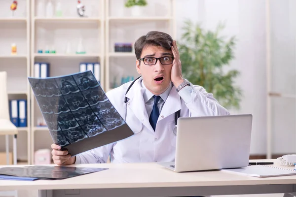 Junger Arzt schaut sich Röntgenbilder in Klinik an — Stockfoto