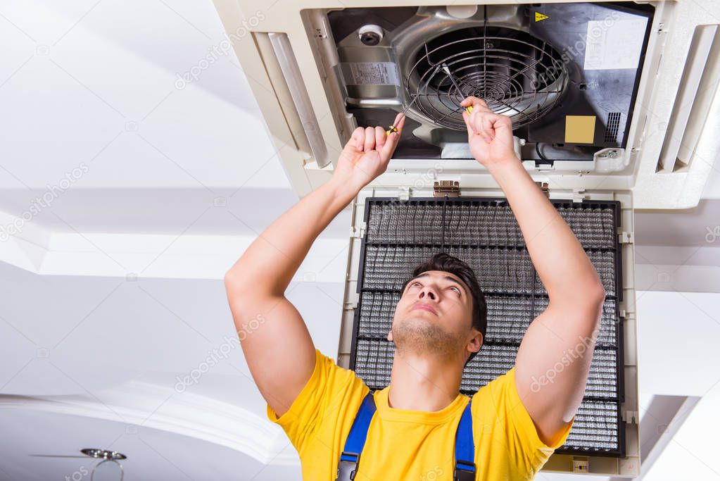 Repairman repairing ceiling air conditioning unit