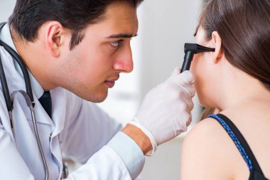 Doktor muayene sırasında hastaların kulaklarını kontrol ediyor.