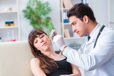 Doktor muayene sırasında hastaların kulaklarını kontrol ediyor.