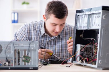 Genç teknisyen atölyede bilgisayar tamir ediyor.