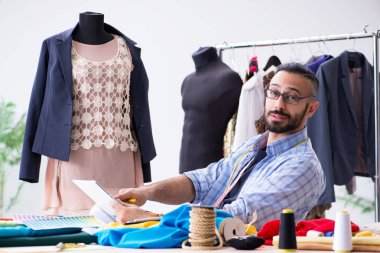 Male tailor working in the workshop on new designs clipart