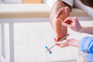 Doktor çekiçle sinir reflekslerini kontrol ediyor